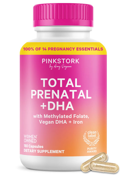 PinkStork Total Prenatal + DHA dietary supplement bottle with a white body, bright pink cap, and pink-to-orange gradient label, shown on a white background with two capsules in front.